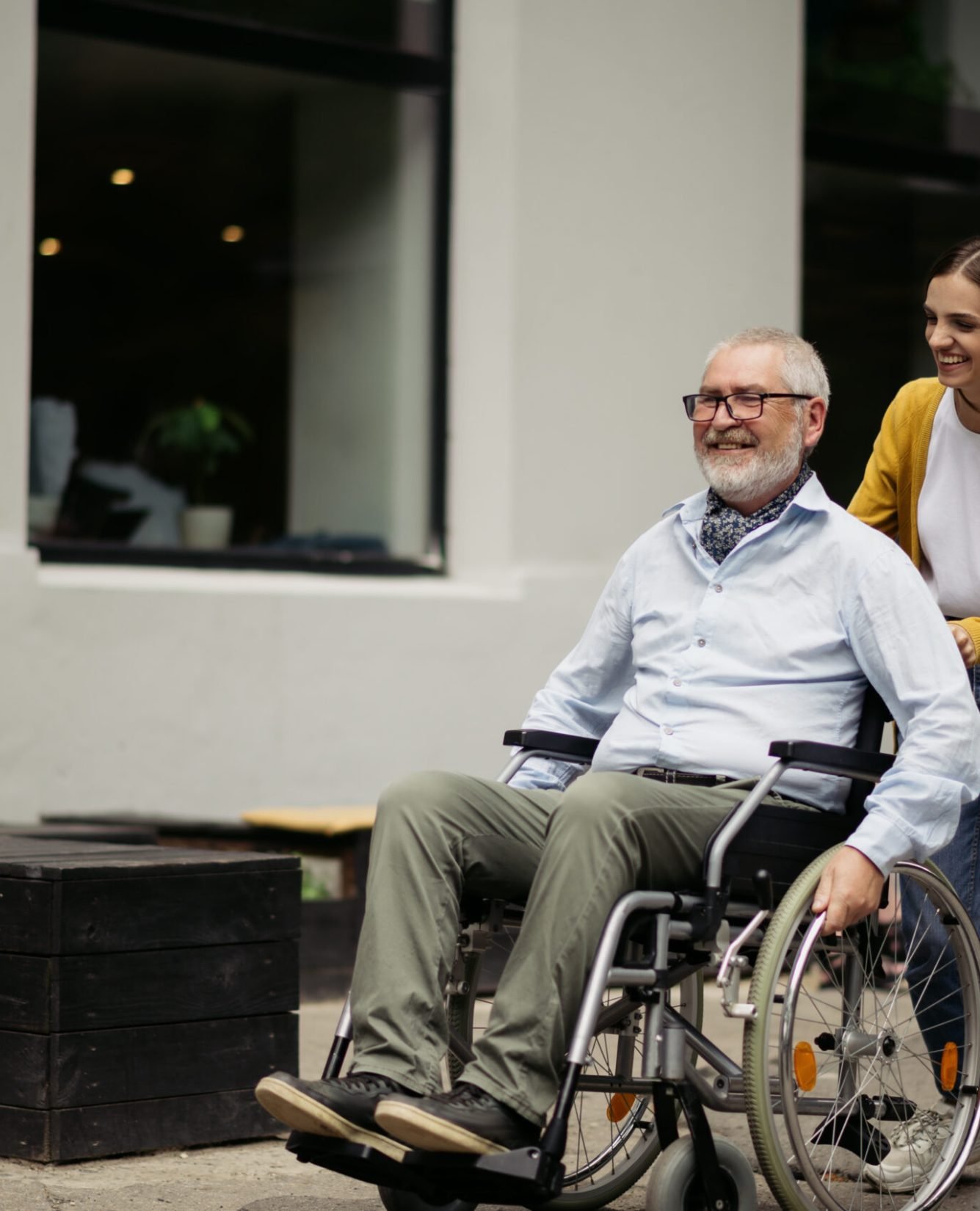 Daughter and disabled father in wheelchair go for a walk. Paralyzed people and disability, handicap overcoming. Handicapped male person and young female guardian in public place