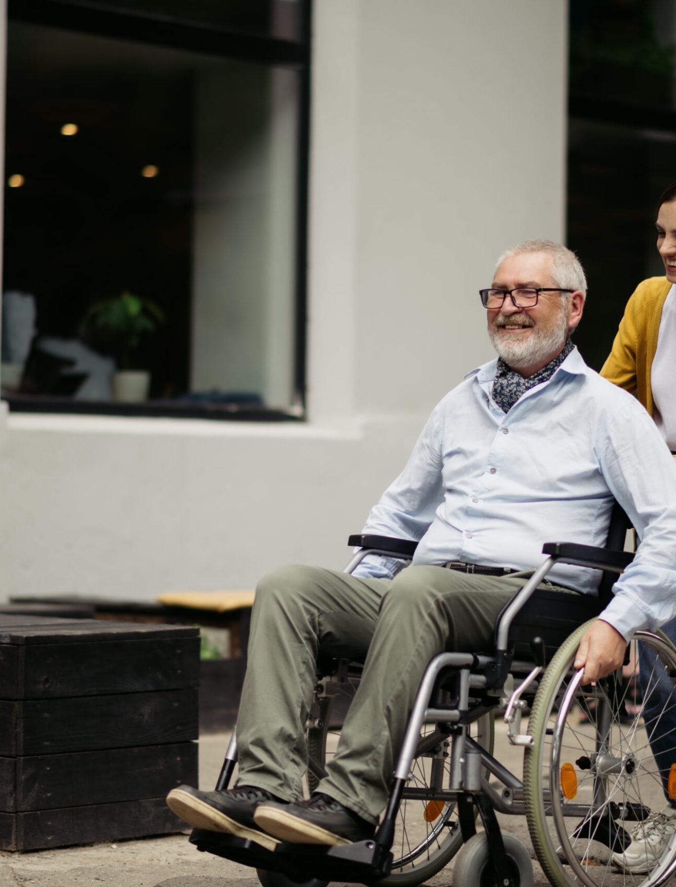 Daughter and disabled father in wheelchair go for a walk. Paralyzed people and disability, handicap overcoming. Handicapped male person and young female guardian in public place